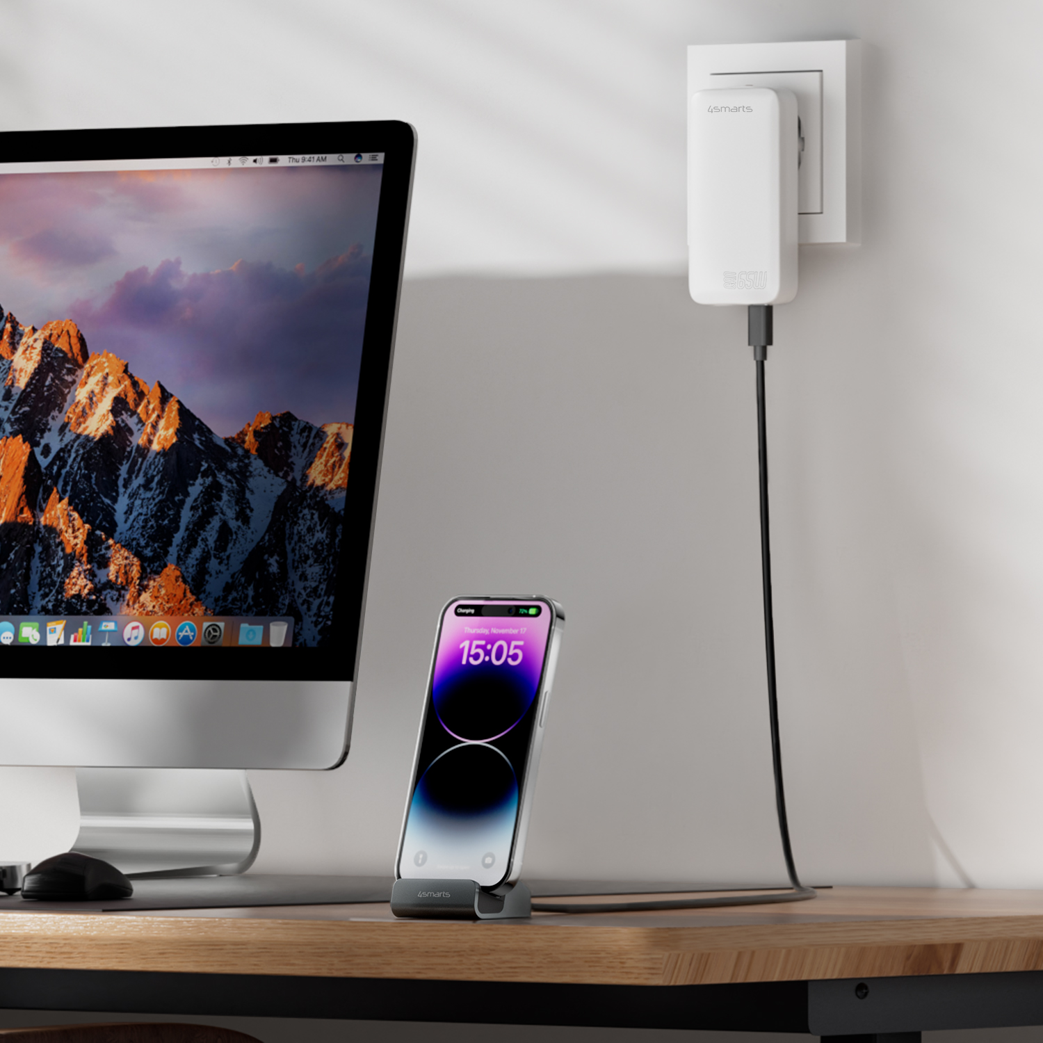 4smarts charging dock with smartphone on a desk next to an iMac – connected to a wall charger via a long USB-C cable.