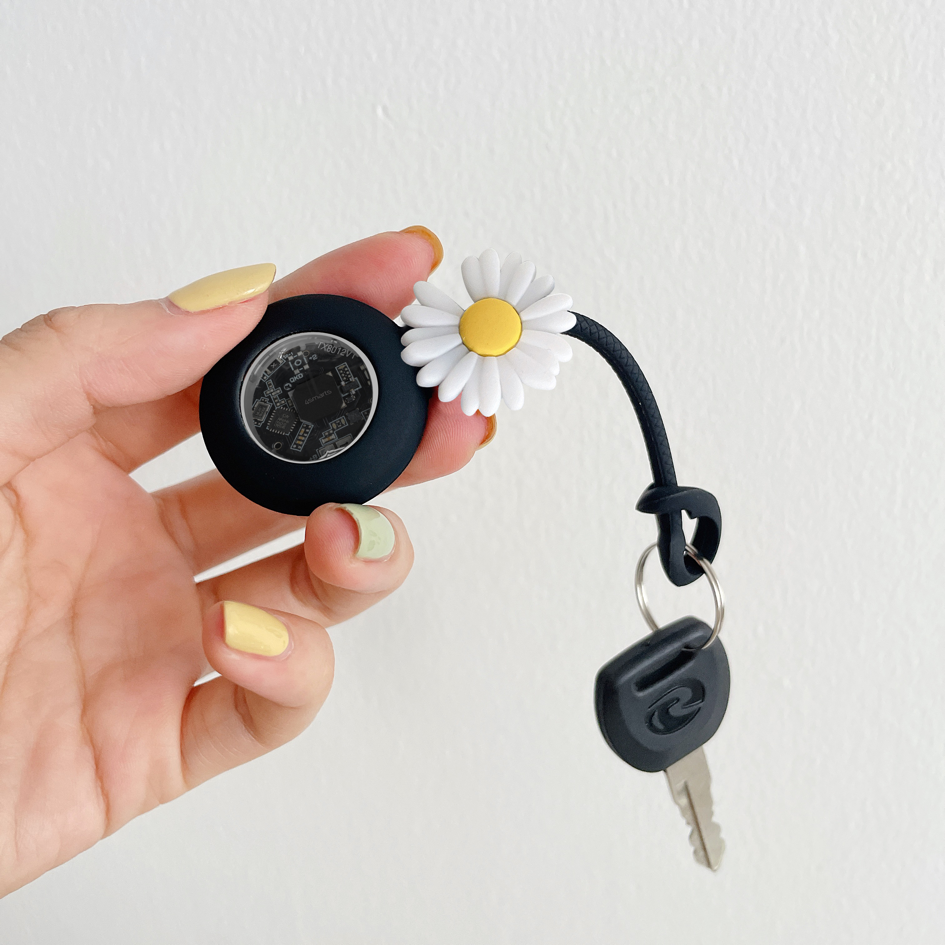 Schwarze AirTag-Hülle mit Gänseblümchen-Design – stilvoller Schutz mit Schlüsselbefestigung