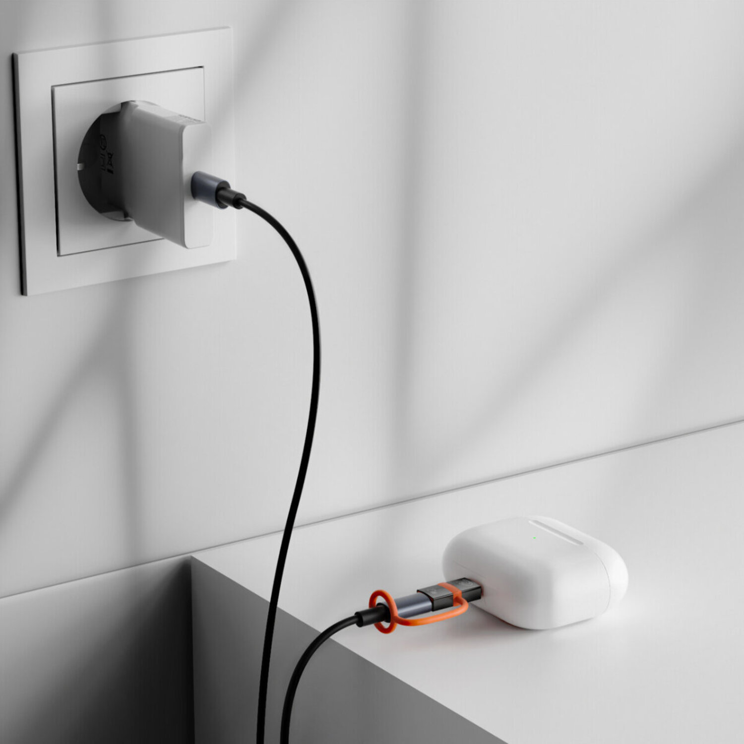 USB-C cable with Lightning adapter plugged into a white wall charger – sturdy connection with orange cable holder.