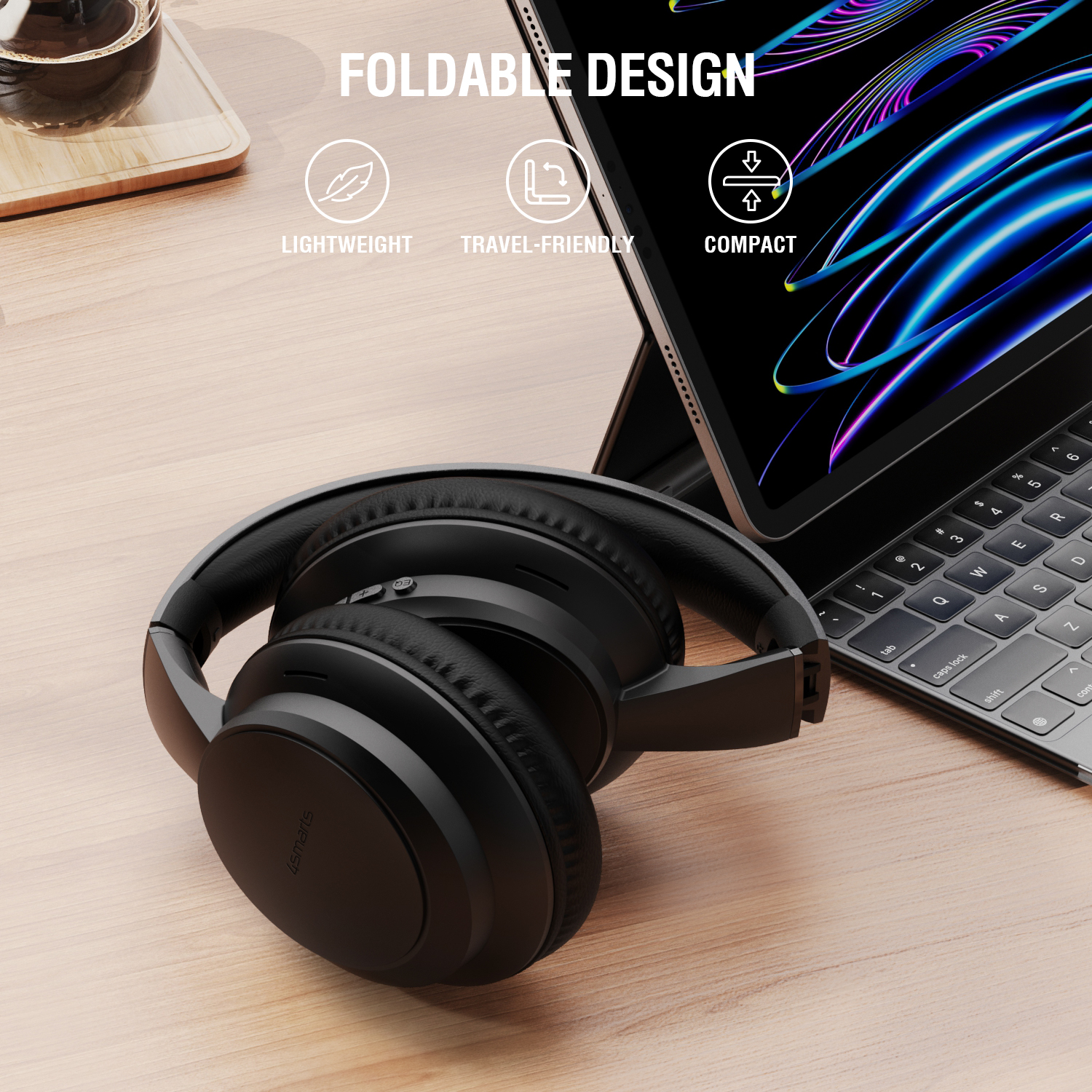 Folded black over-ear headphones placed next to a tablet with keyboard on a desk. Text highlights the foldable, compact, and lightweight design.

