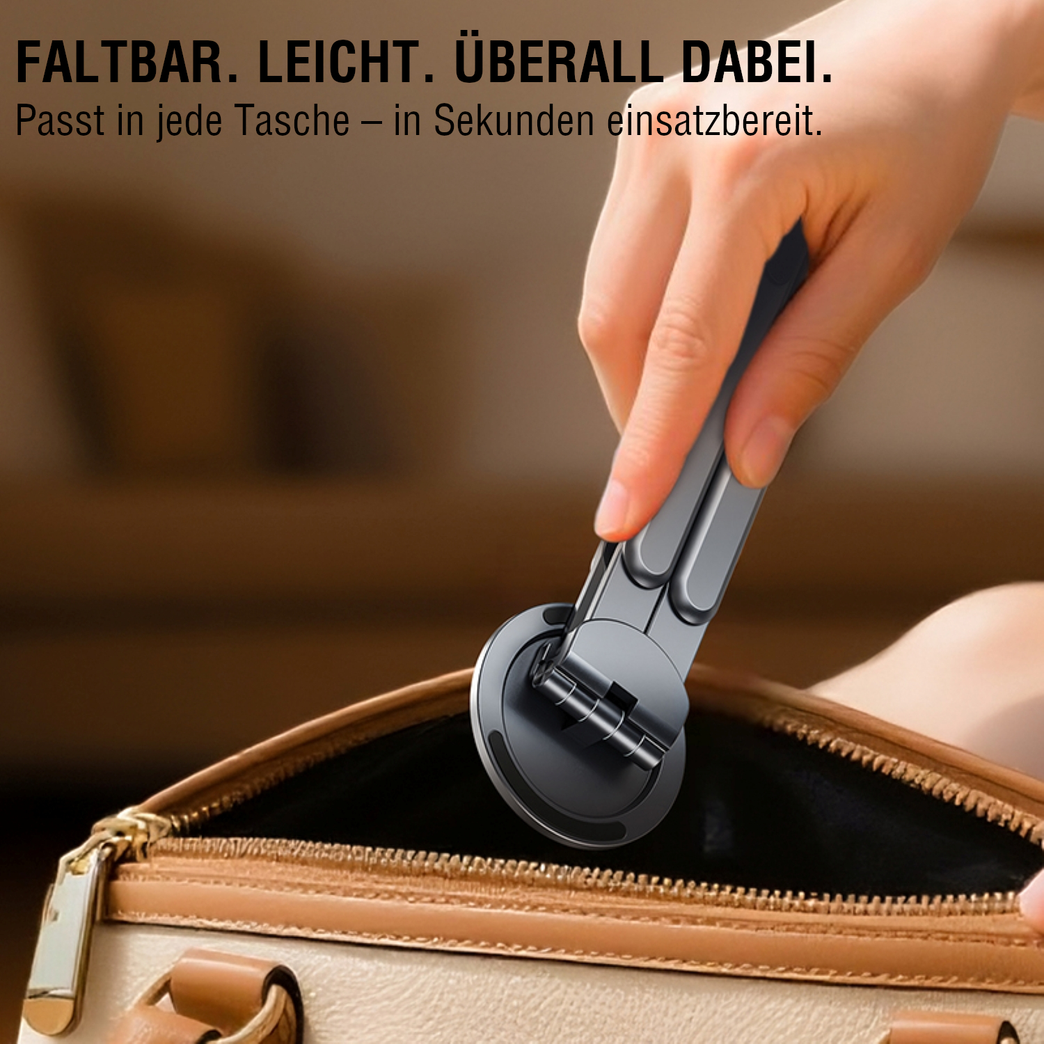 Hand legt den kompakten, zusammengeklappten Gerätehalter in eine Handtasche – leicht und transportabel.
