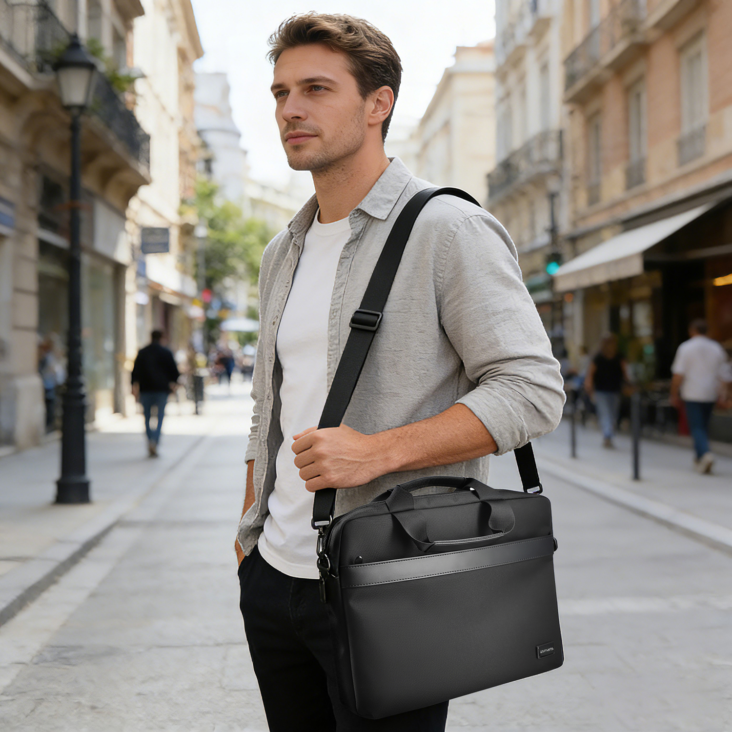 Elegant black 15–16 inch notebook bag worn with a shoulder strap by a person in business attire in an urban environment
